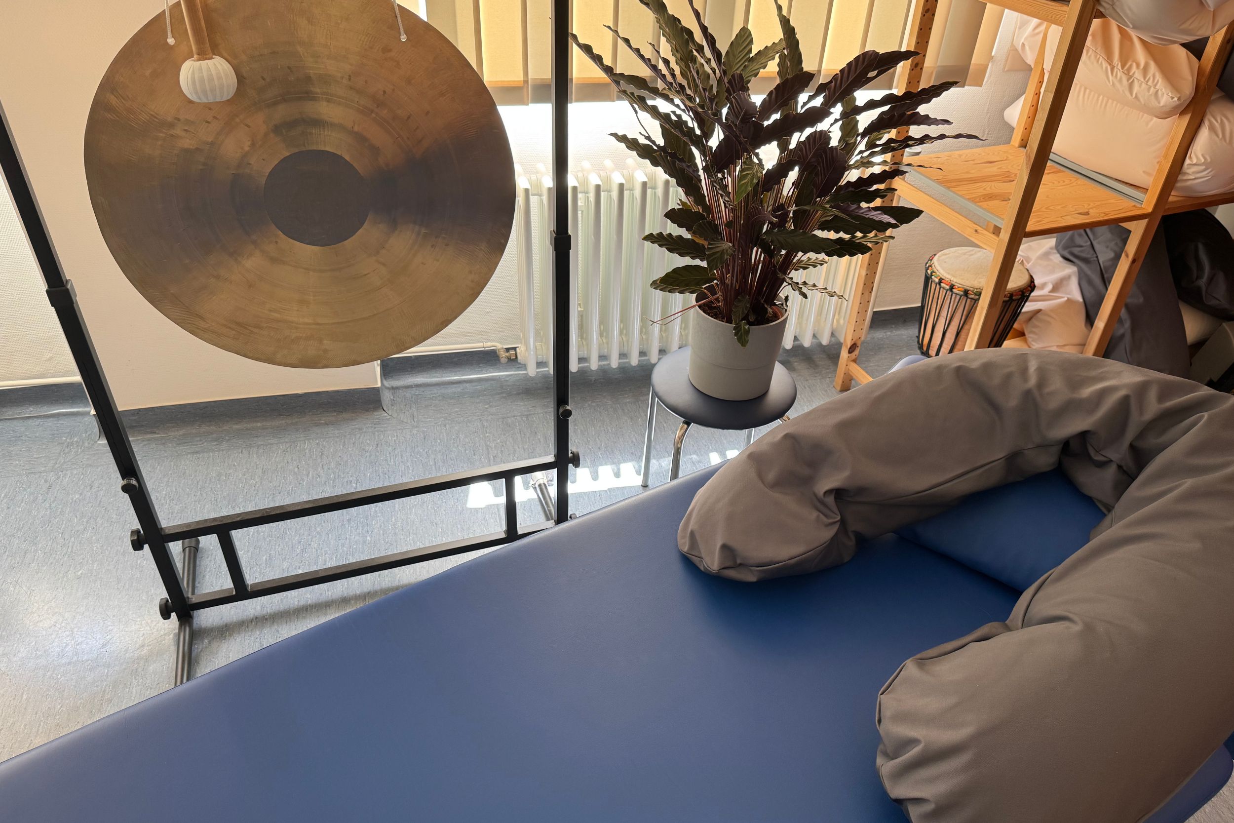 Warmes freundliches Therapiezimmer mit Behandlungsliege und asiatischem Handgong